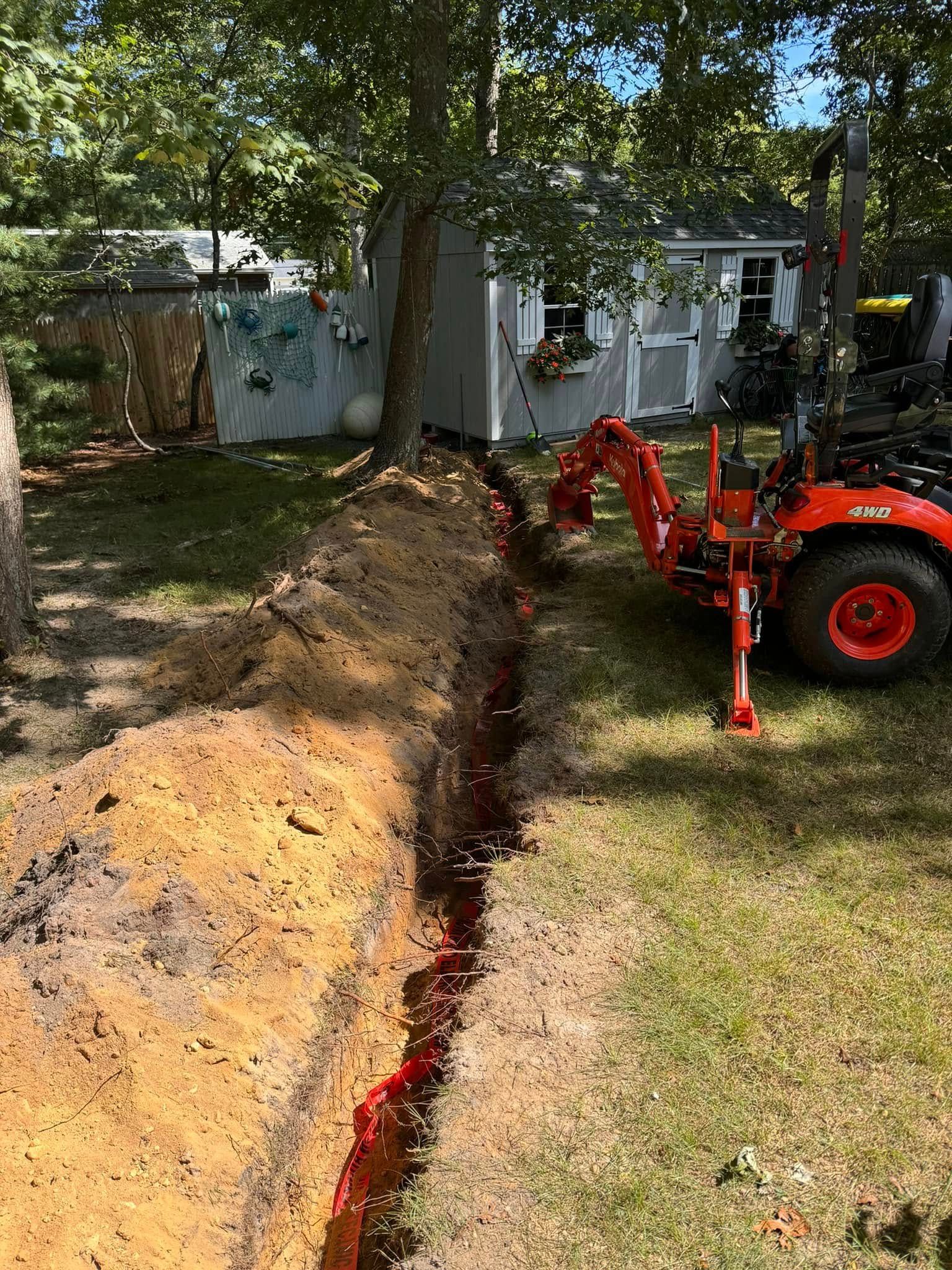 A tractor is digging a hole in the ground in a yard.