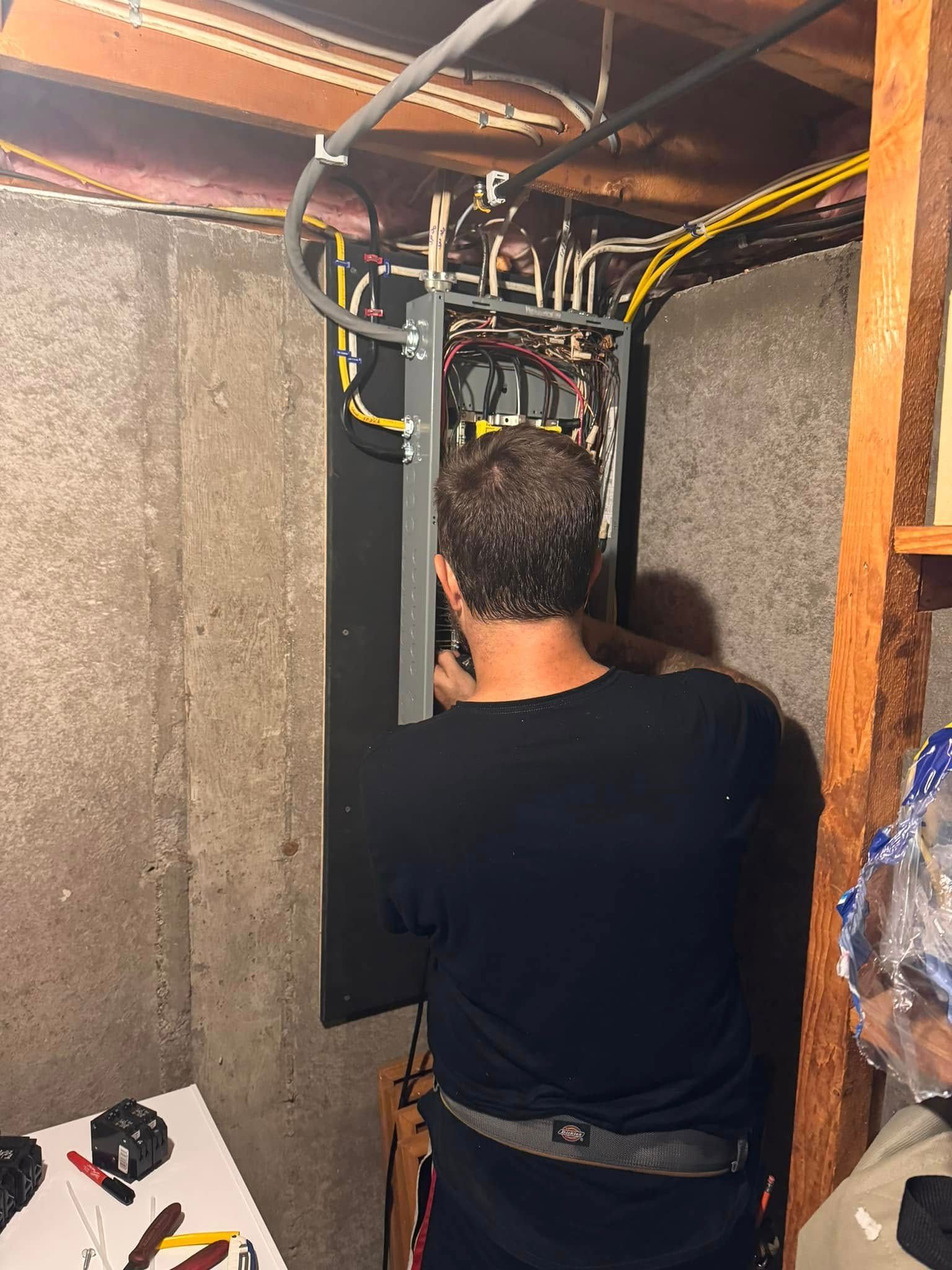 A man is working on an electrical box in a basement.