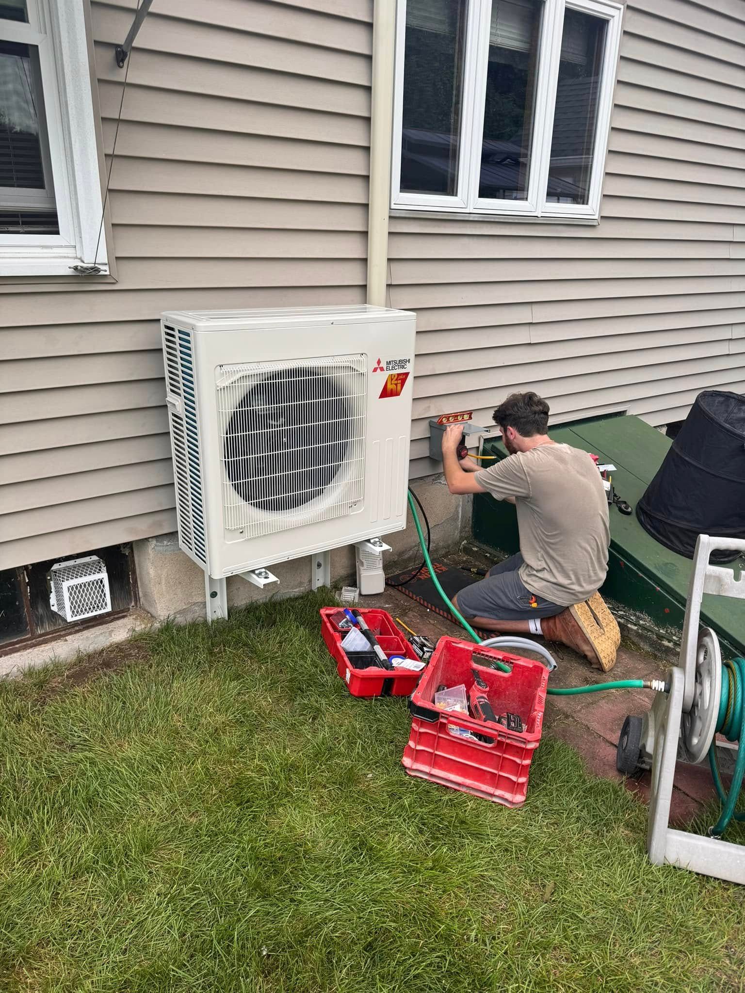 A man is working on an air conditioner outside of a house.