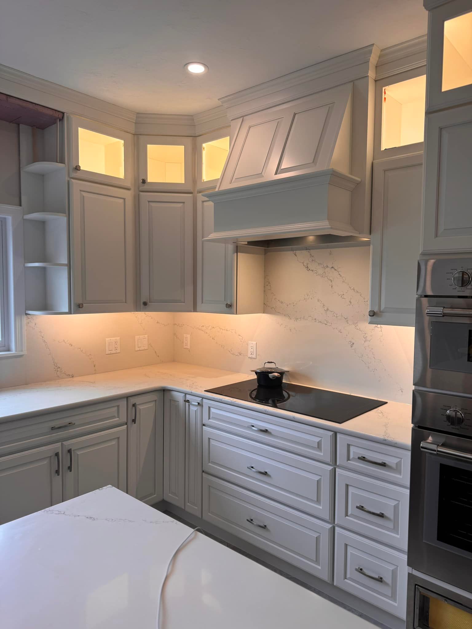 A kitchen with white cabinets, stainless steel appliances, and a stove top oven.