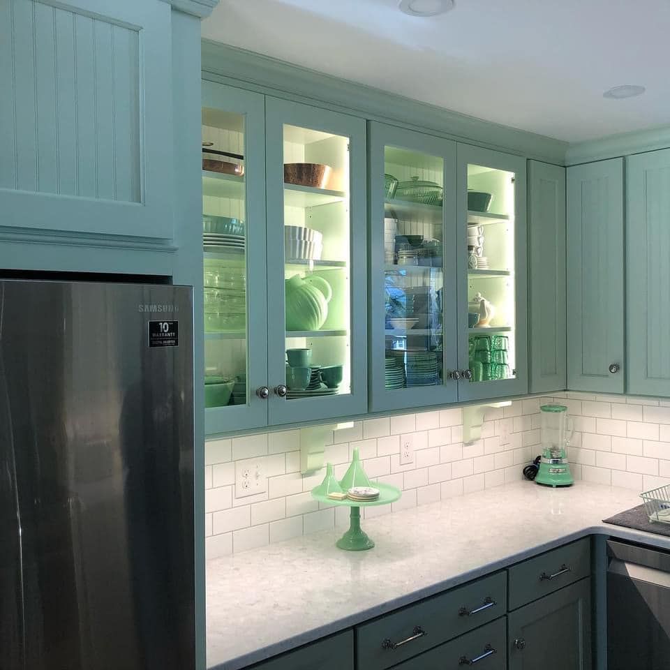 A kitchen with green cabinets and a stainless steel refrigerator