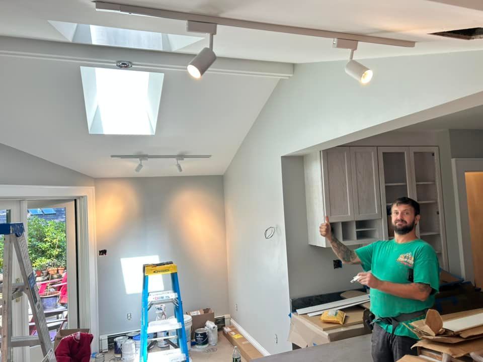 A man in a green shirt is standing in a kitchen with a ladder.