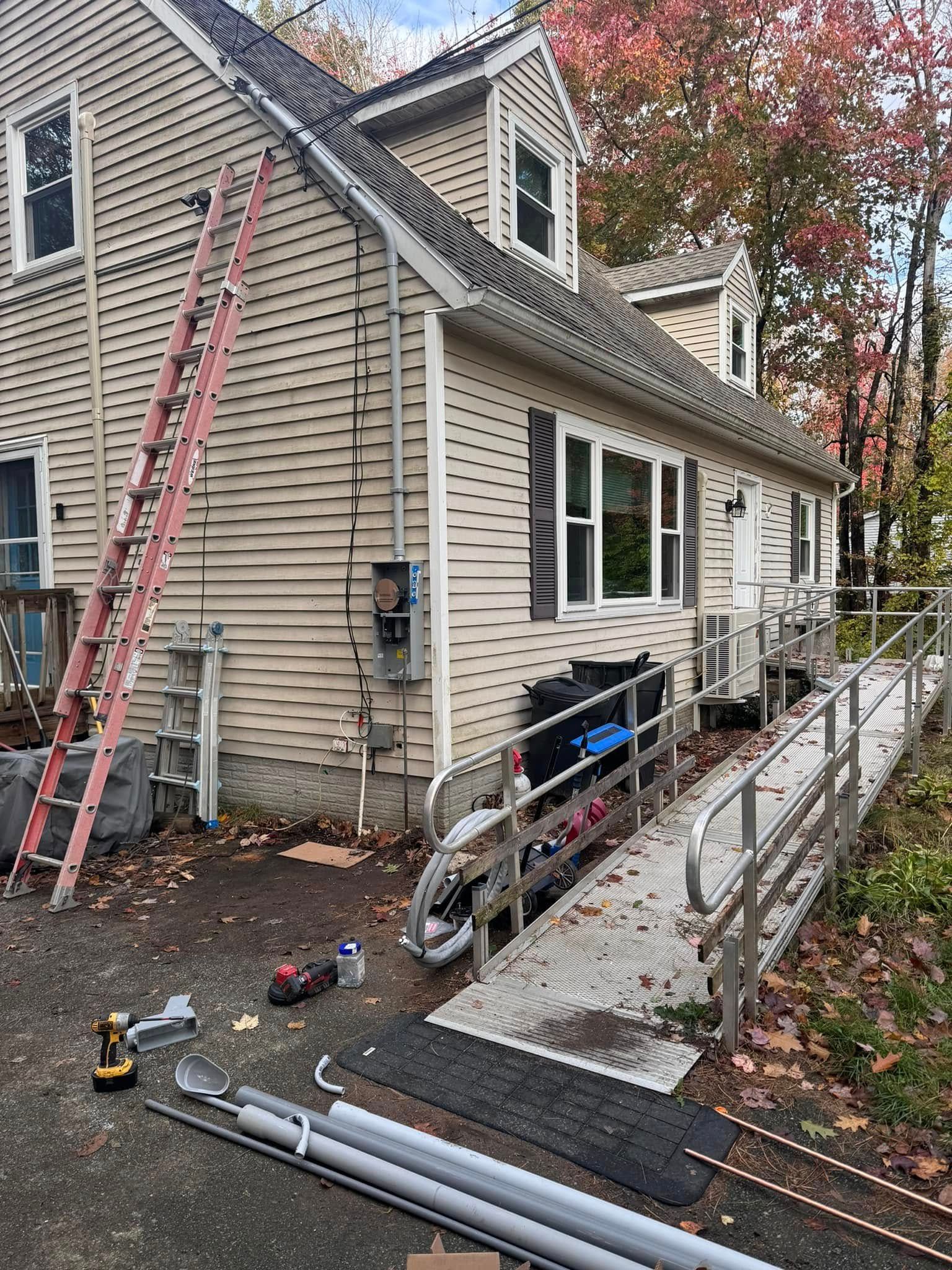 A ladder is sitting on the side of a house next to a ramp.