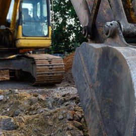 A yellow excavator is digging a hole in the ground.