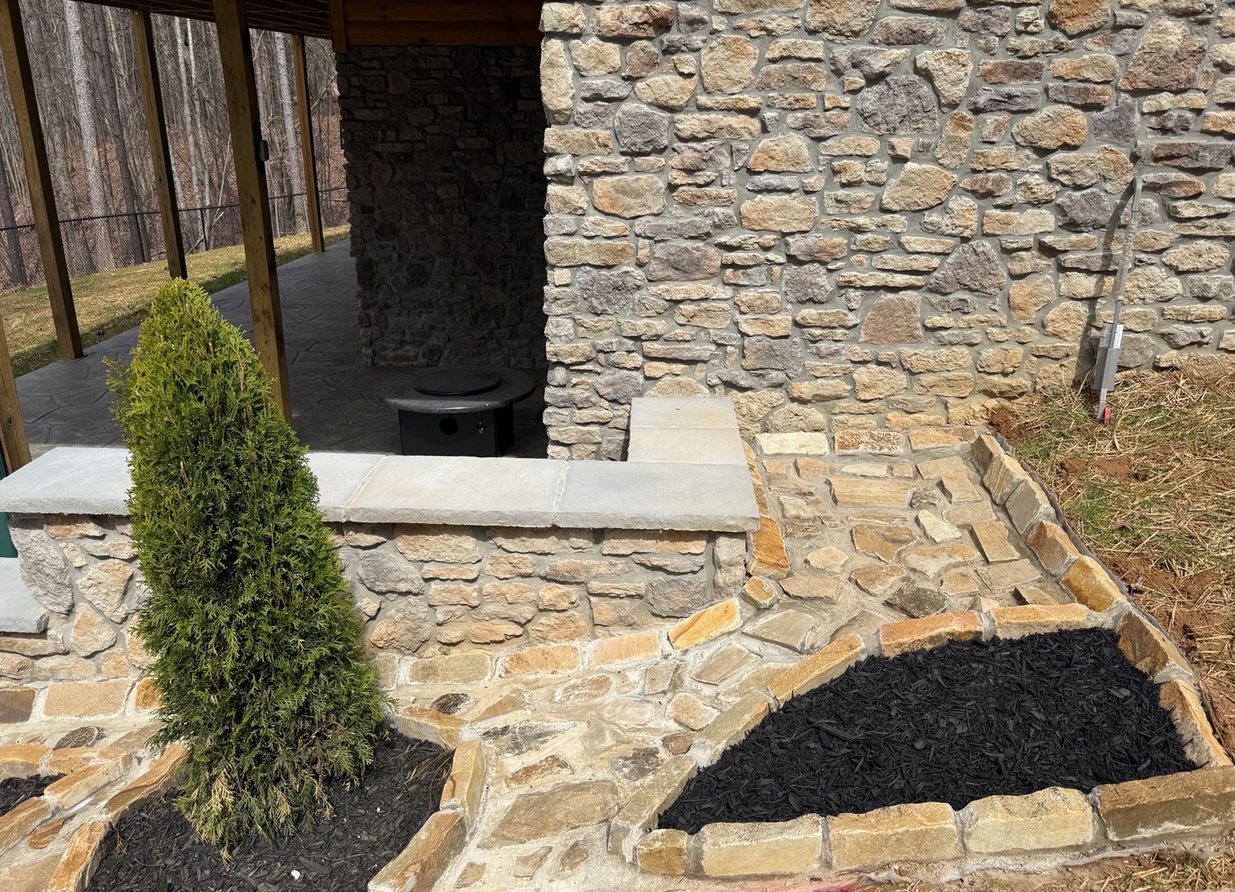A stone wall with a patio in front of it.