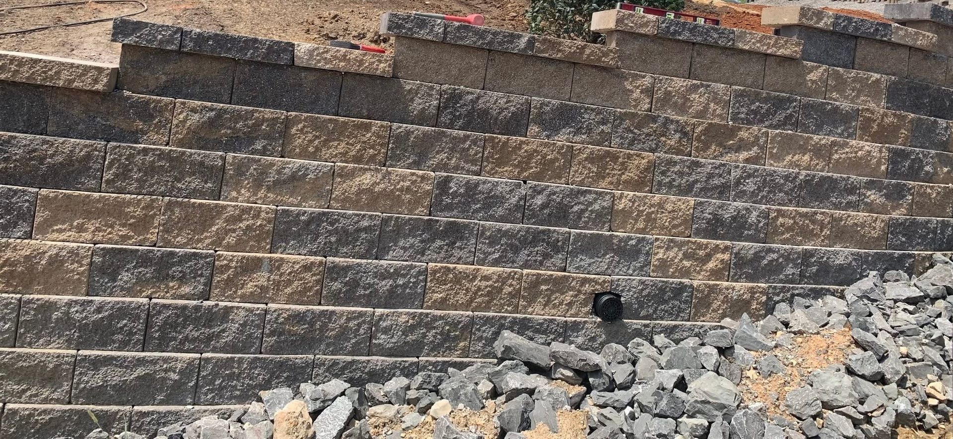 A brick wall is being built on top of a pile of rocks.
