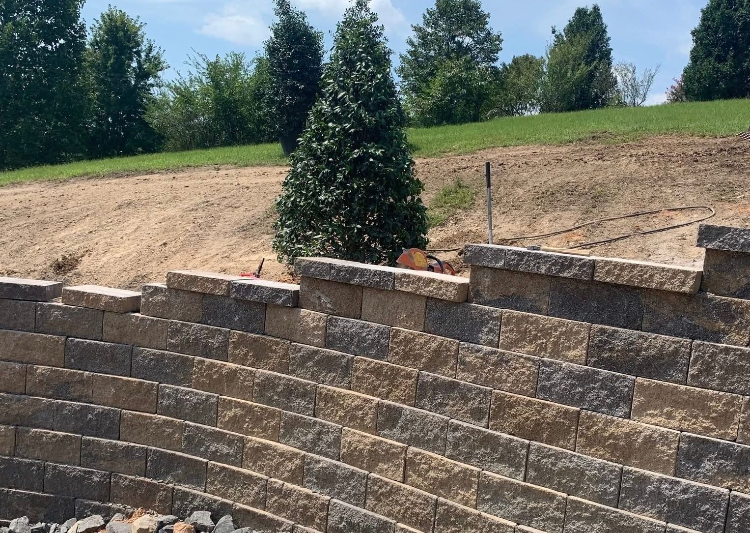 A brick wall is being built on top of a dirt hill.