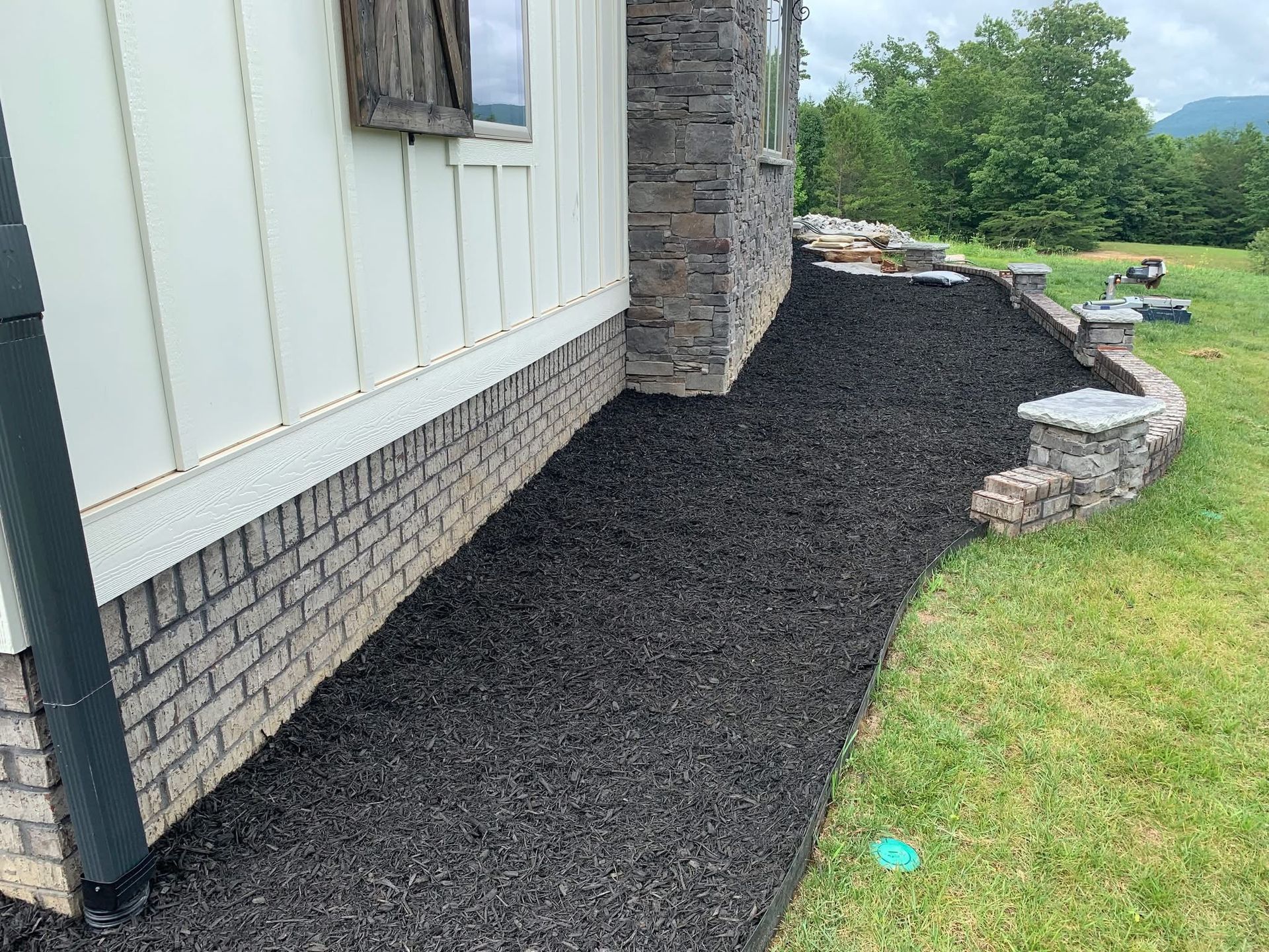 A sidewalk leading to the side of a house with black mulch.
