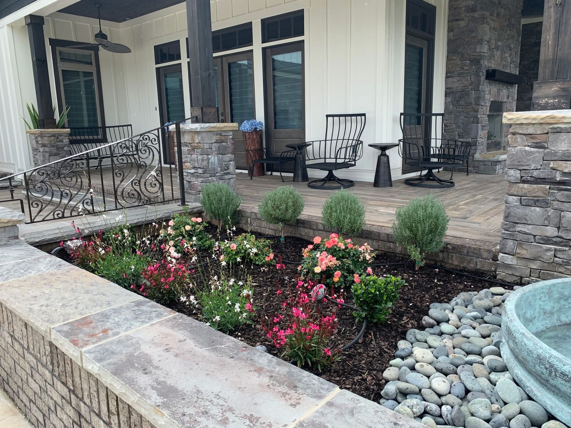 A patio with flowers and rocks in front of a house.