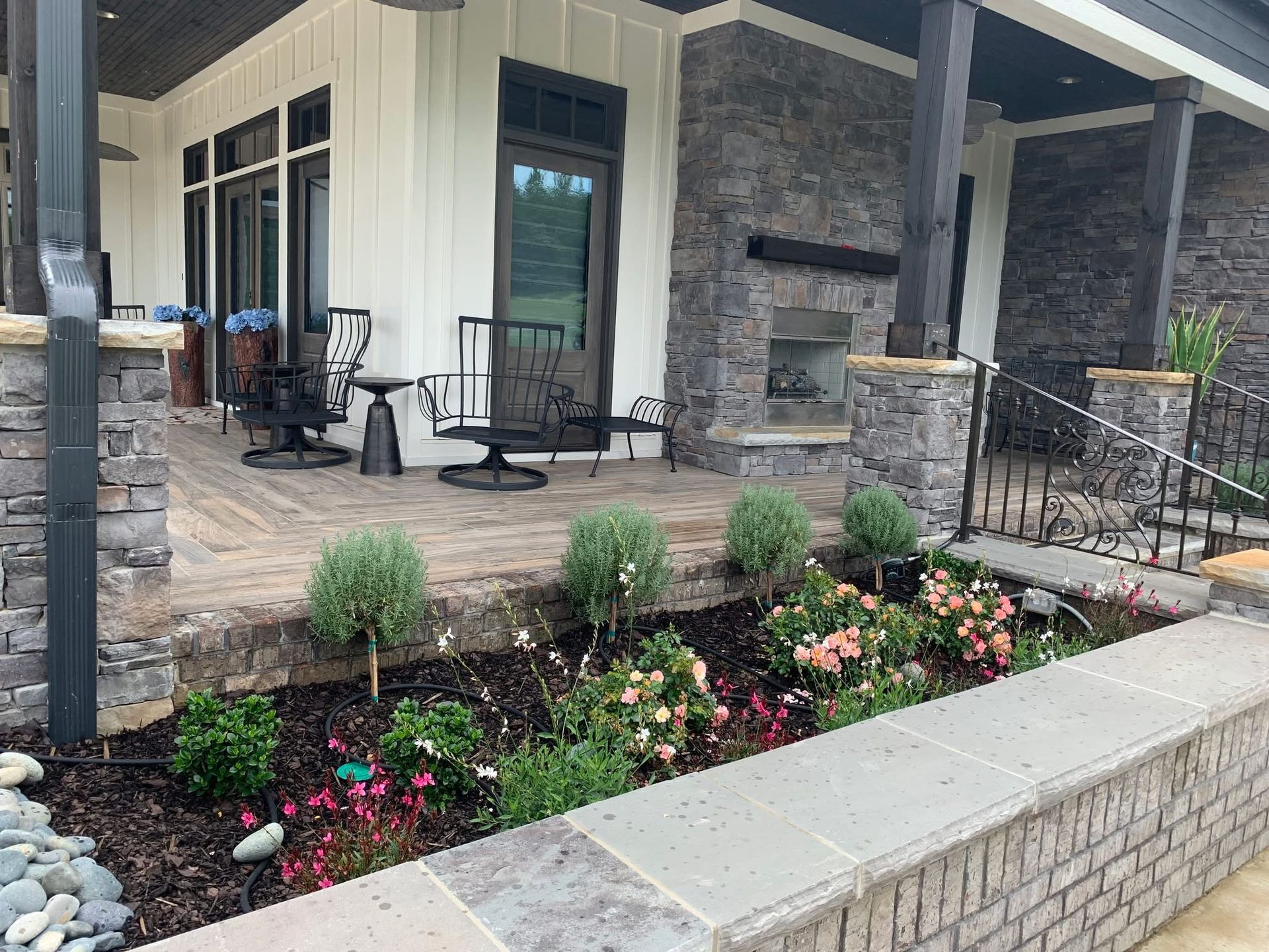 A patio with a fireplace and flowers in front of a house.
