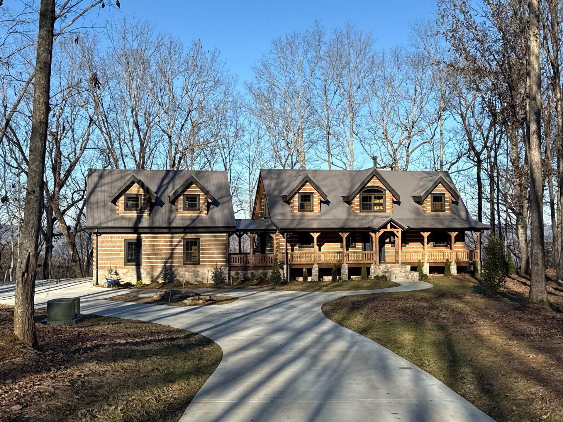 A large house with a driveway leading to it is surrounded by trees.