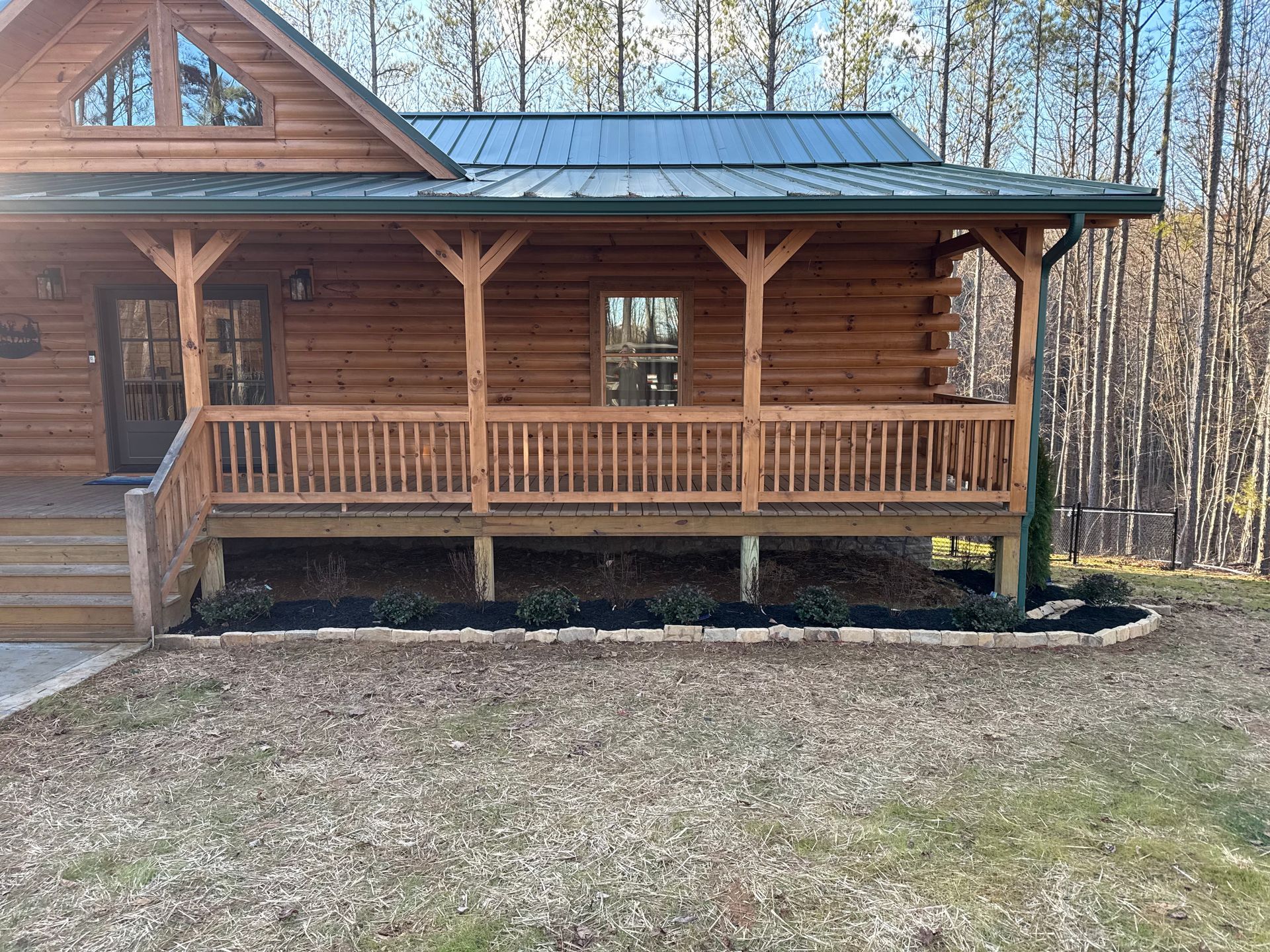 A log cabin with a large porch in the middle of the woods.