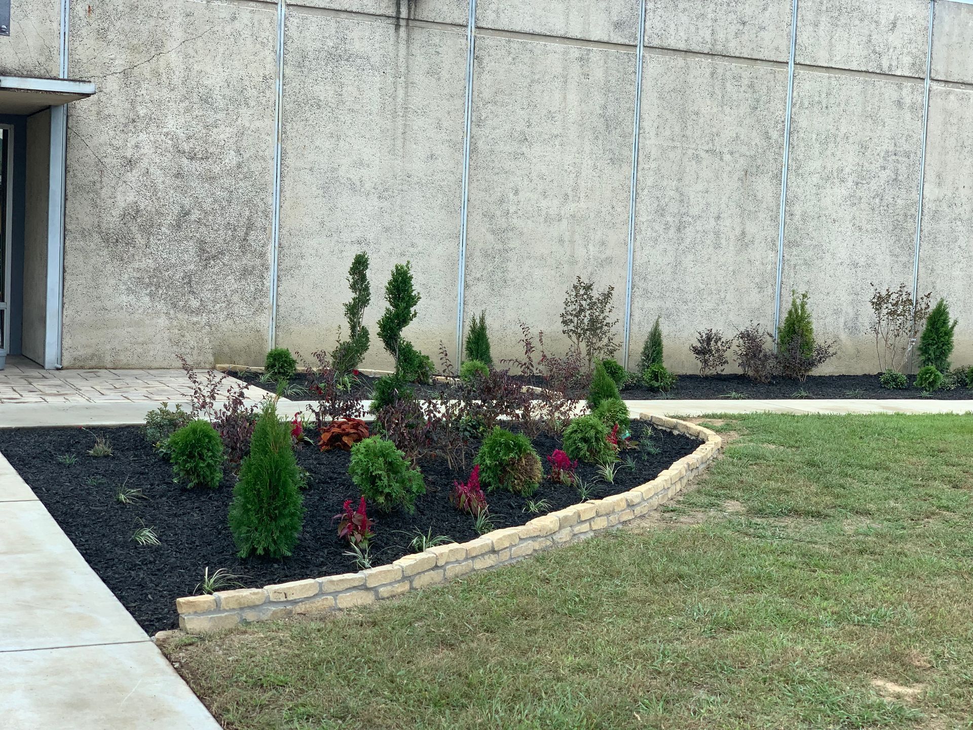 A concrete wall with a garden in front of it.