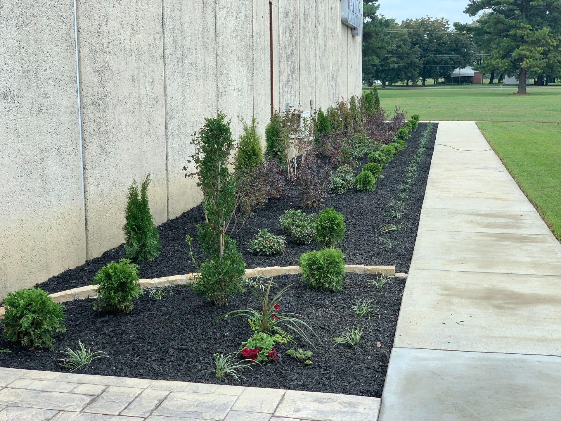 A sidewalk with a garden in front of a building.