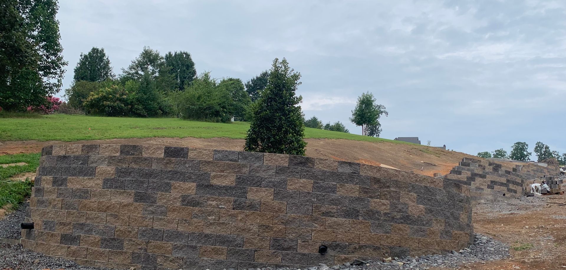 A brick wall is being built in the middle of a field.
