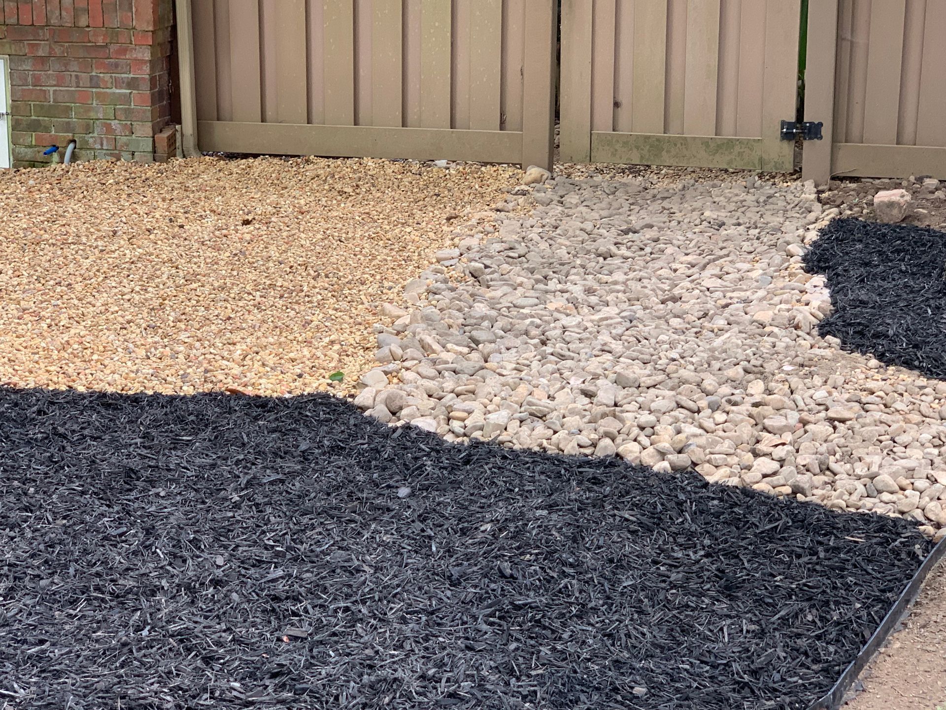 A pile of gravel is sitting next to a fence.