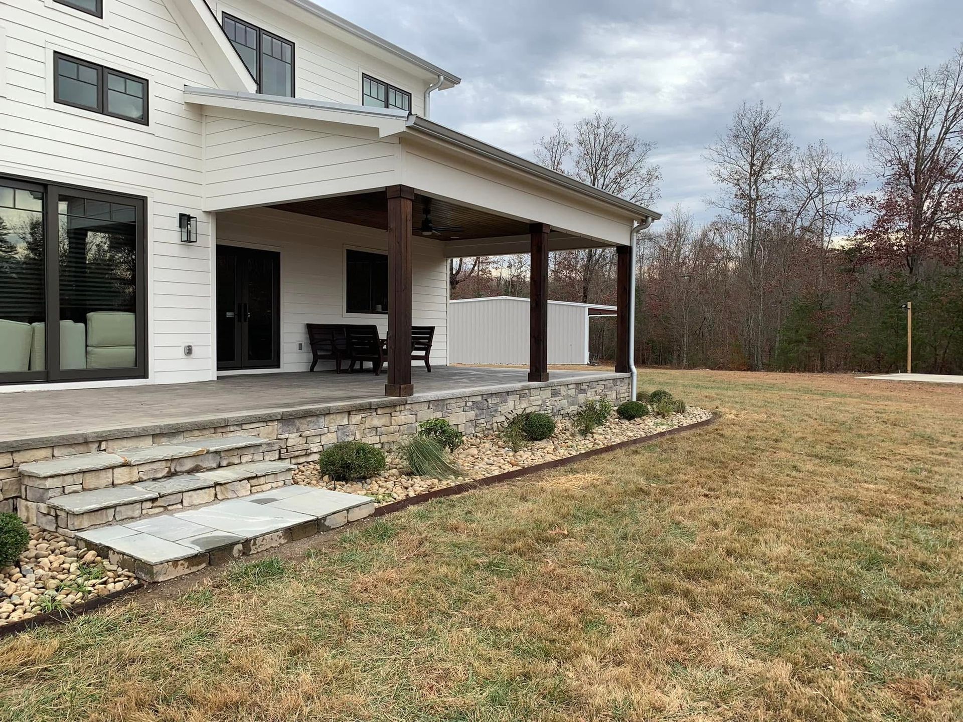 A large white house with a covered porch and stairs in the backyard.