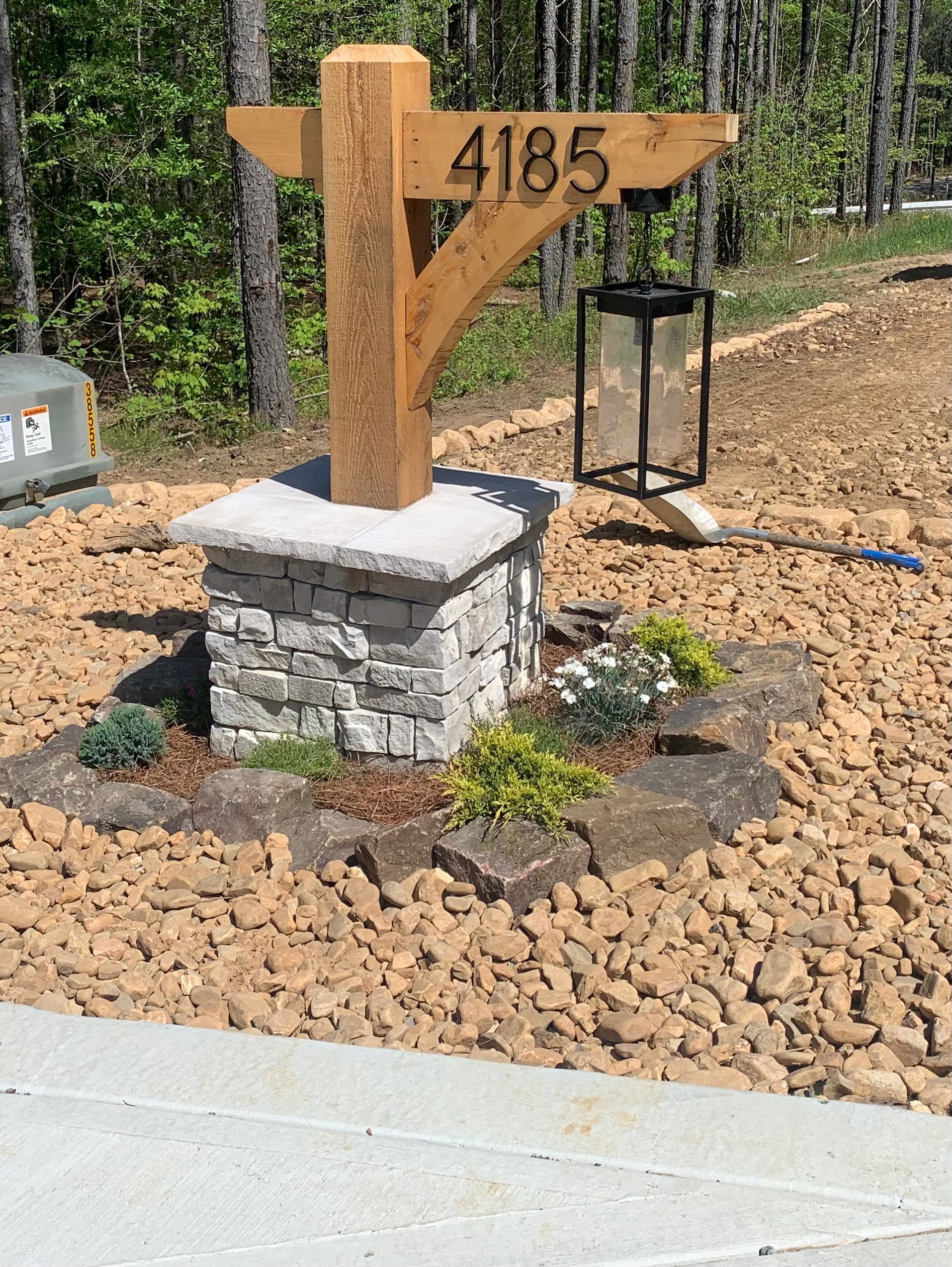 A wooden mailbox is sitting on top of a stone pillar.