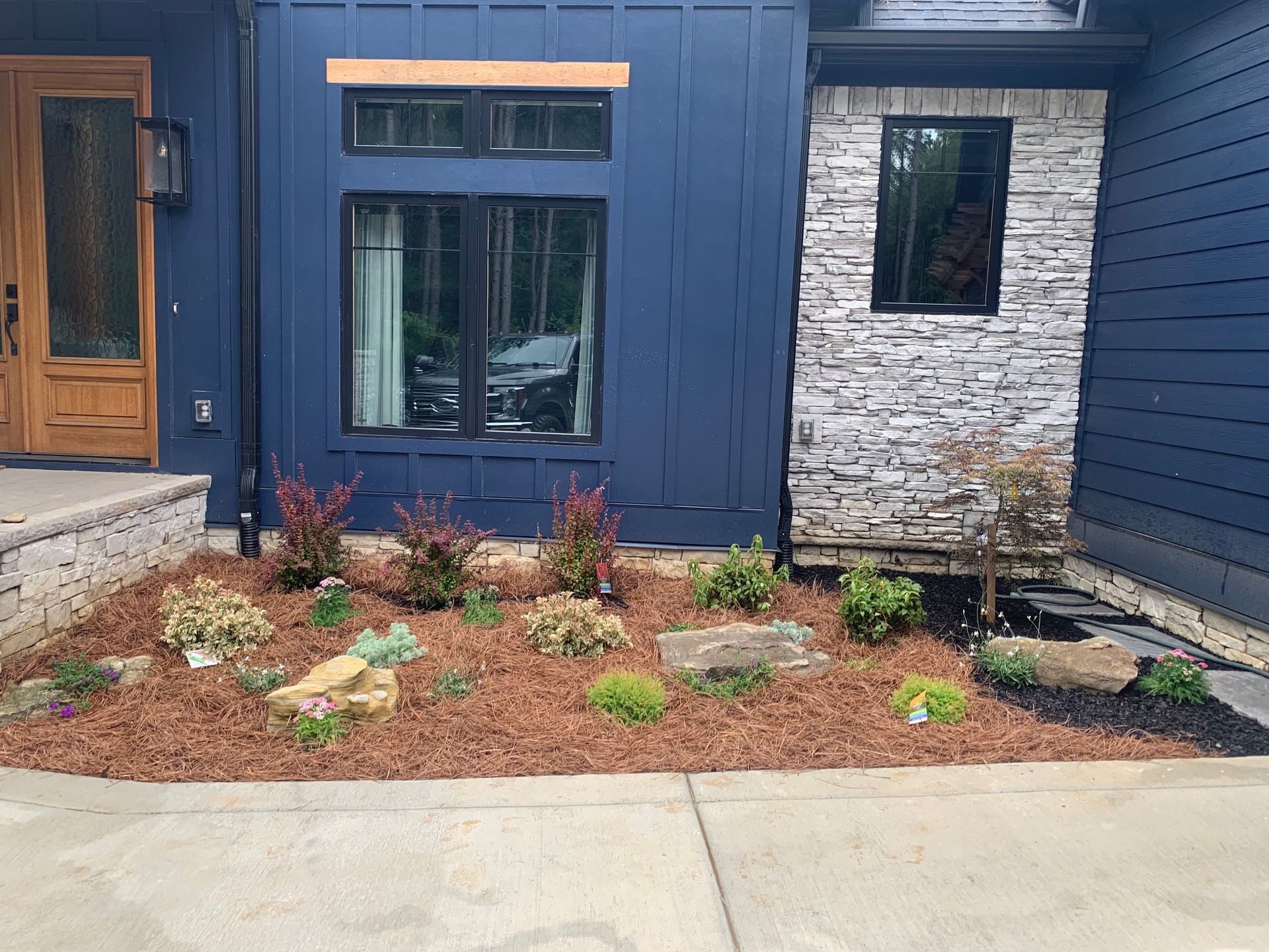 A blue house with a stone wall and a garden in front of it.