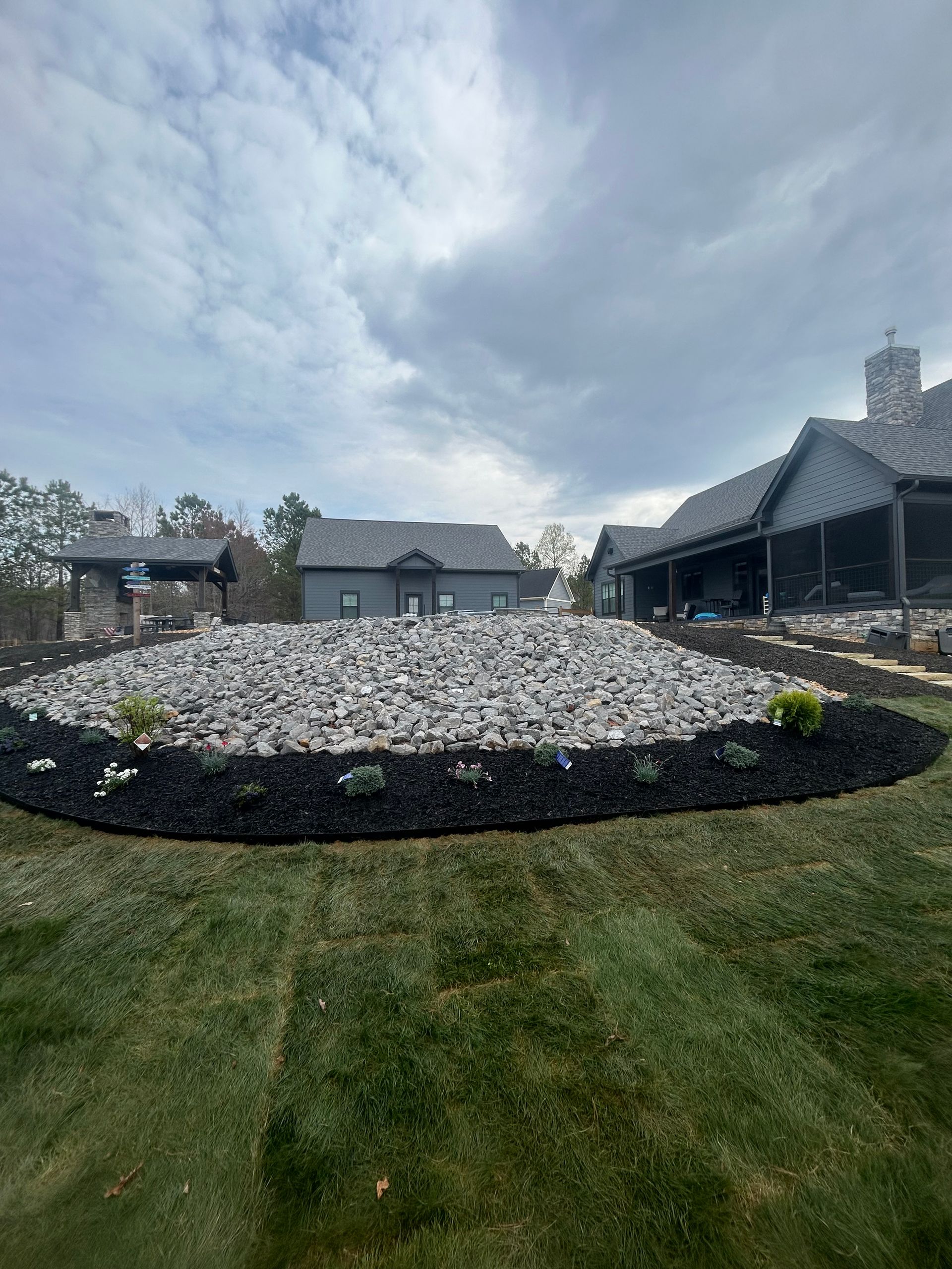 There is a large rock in the middle of the yard in front of a house.