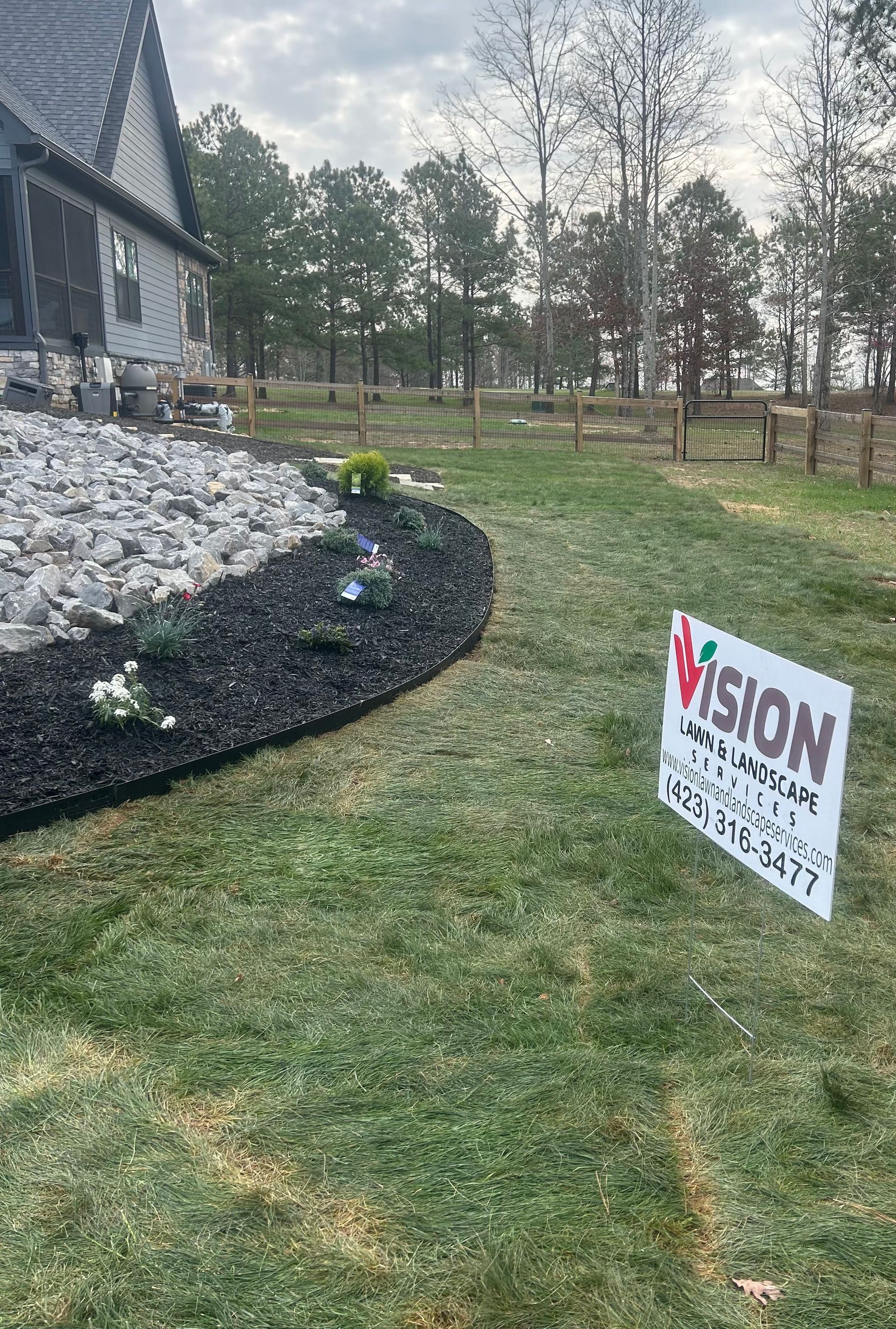 A sign is sitting in the grass in front of a house.