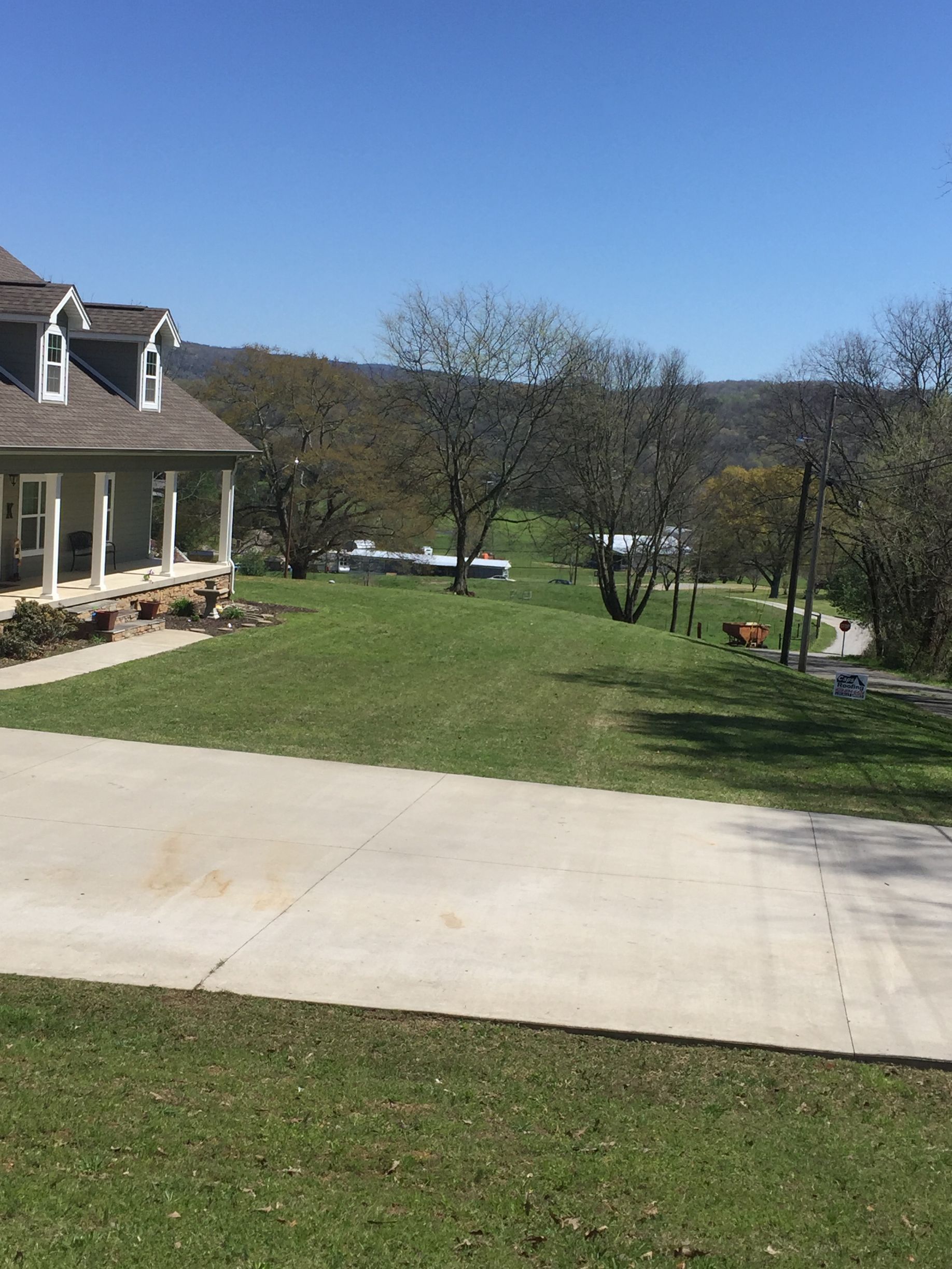 A house with a driveway leading to it is surrounded by grass and trees.