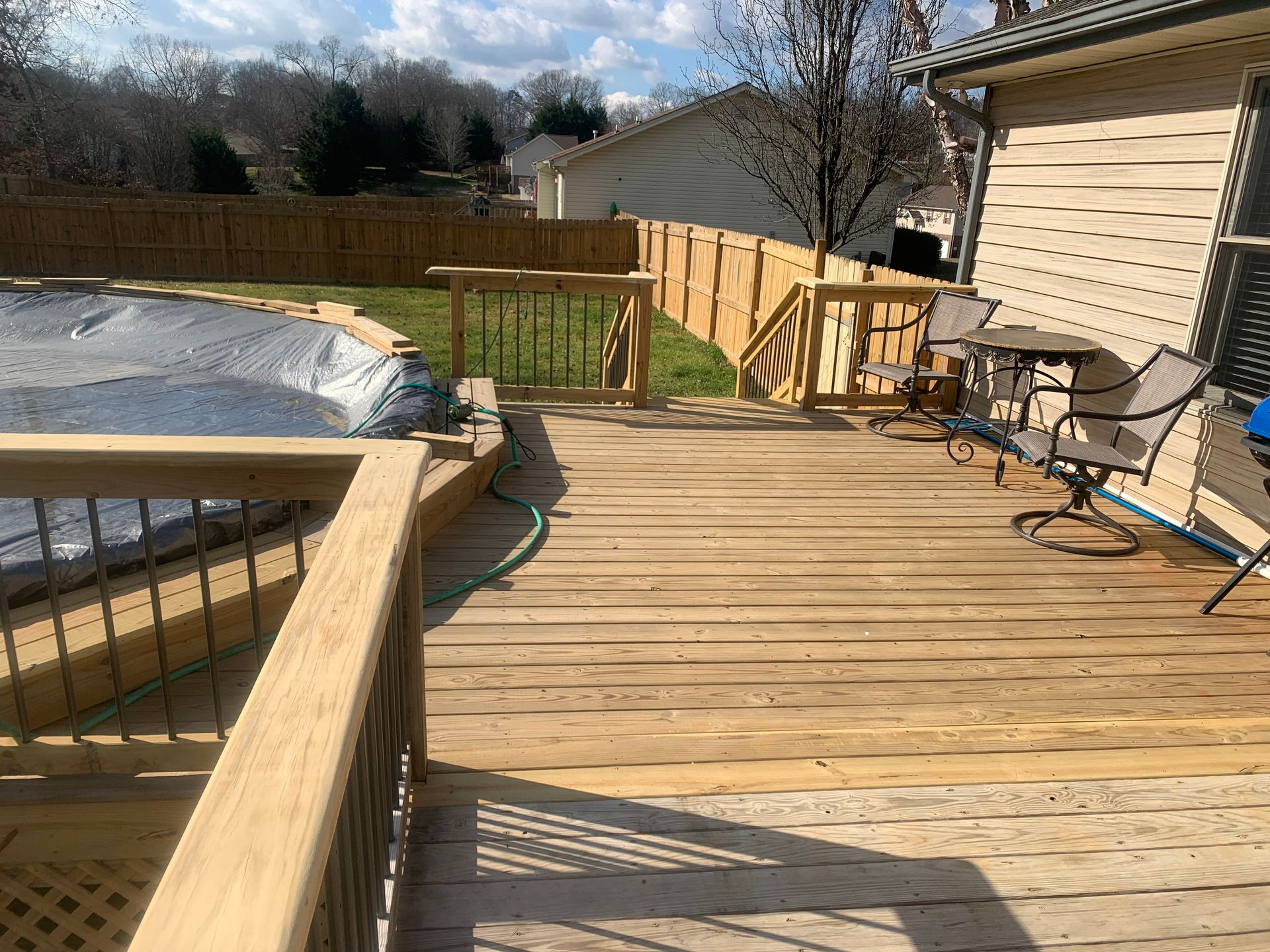 A wooden deck with a table and chairs next to a pool.