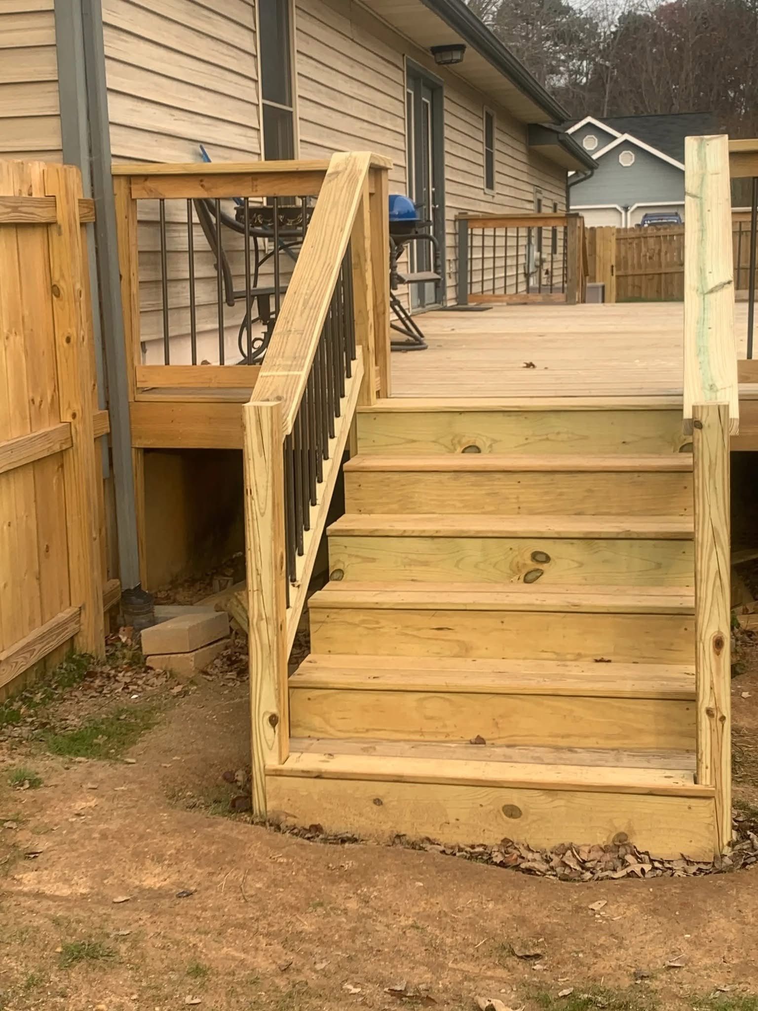 A wooden deck with stairs leading up to it next to a house.