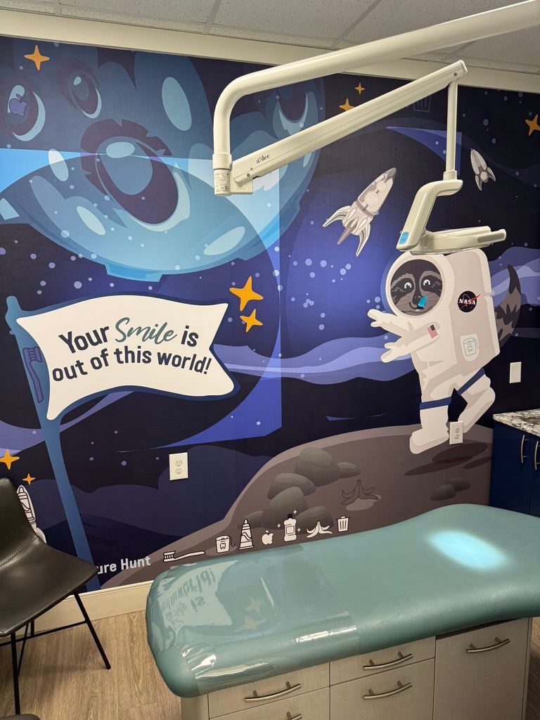 Dentist's office with space-themed vinyl wall wrap. Astronaut, rocket, and banner saying