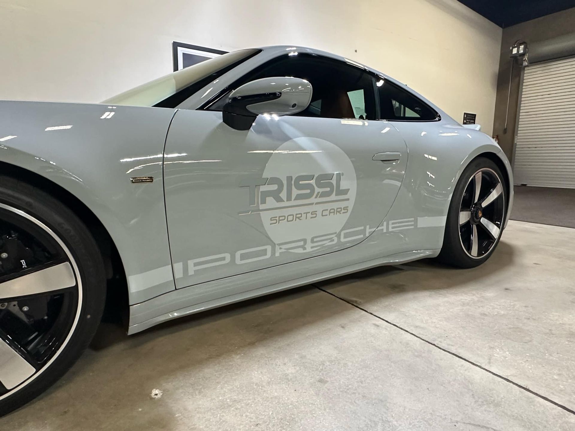 a grey porsche sports car is parked in a garage