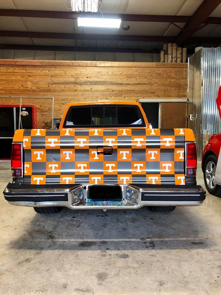 A truck with a checkered pattern on the back is parked in a garage