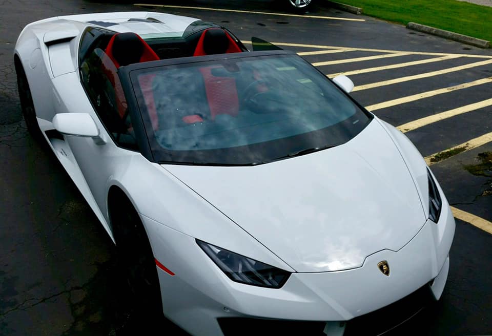 A white sports car with red seats is parked in a parking lot
