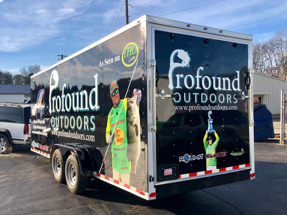A trailer for profound outdoors is parked in a parking lot.