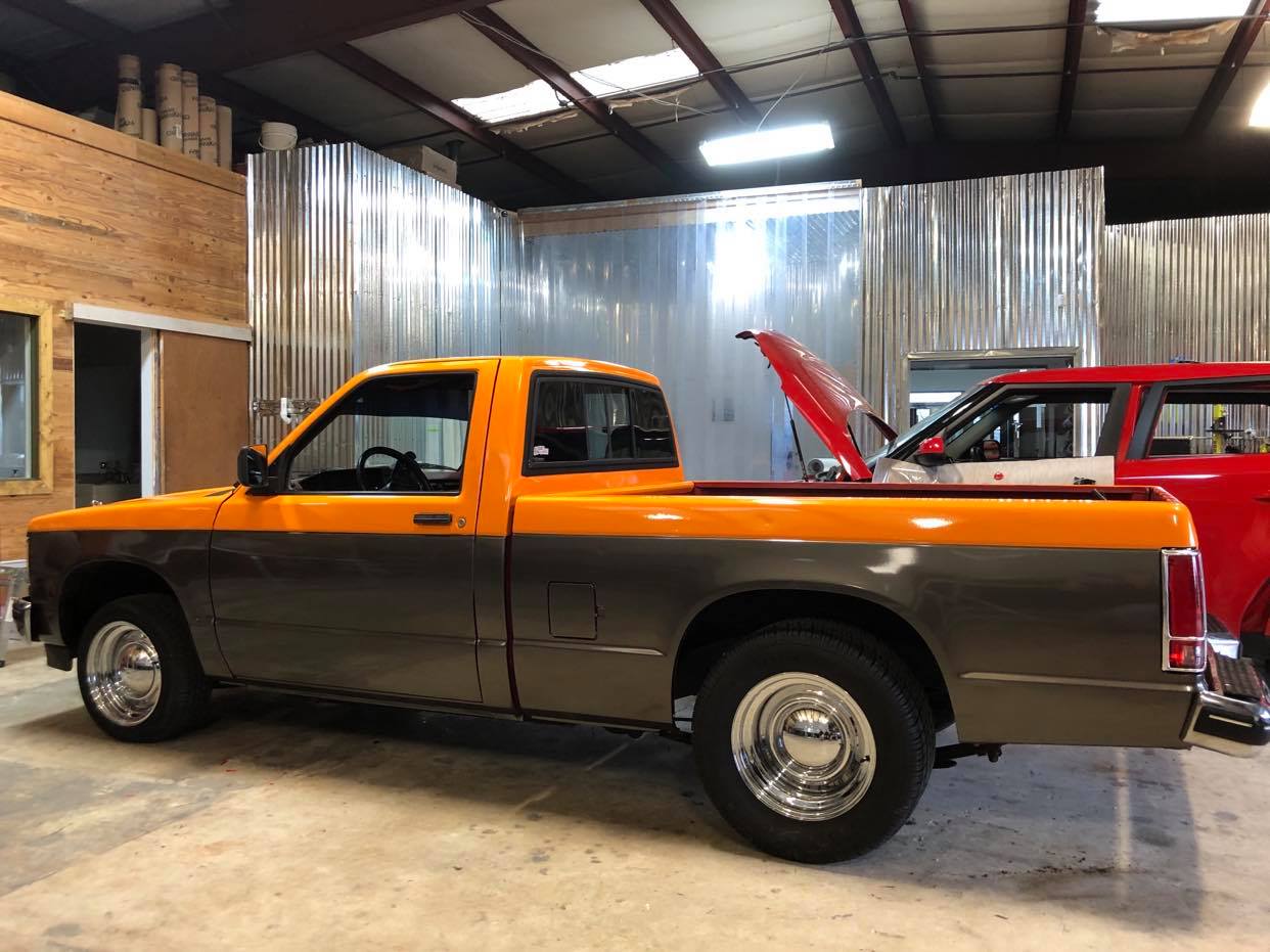 A yellow and gray truck is parked in a garage.