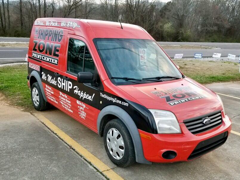 A red van that says shipping zone is parked in a parking lot