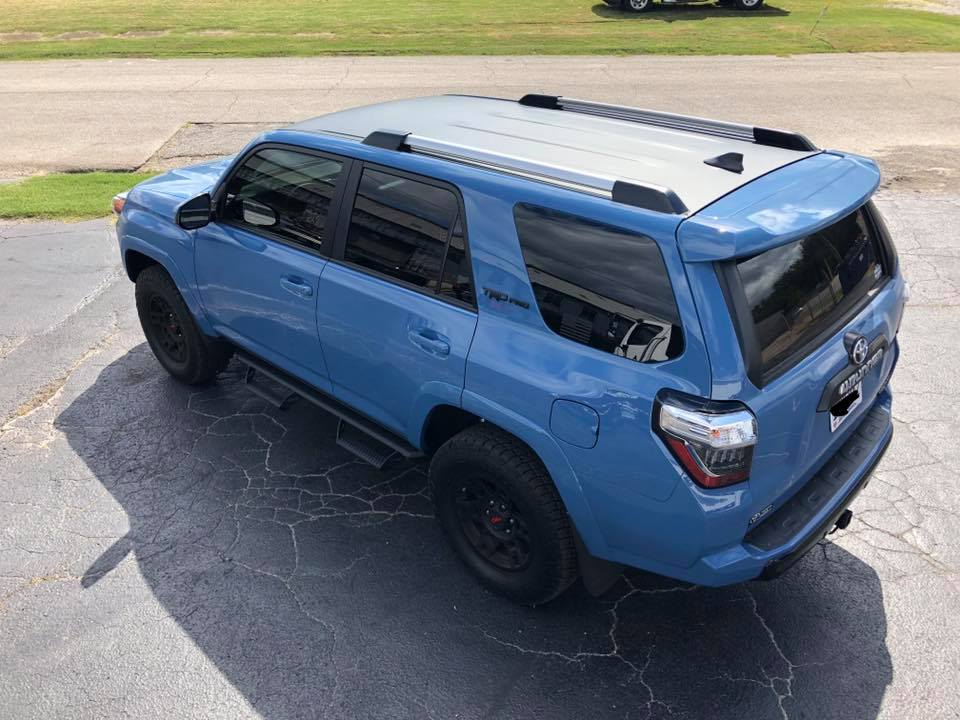 A blue toyota 4runner is parked in a driveway.