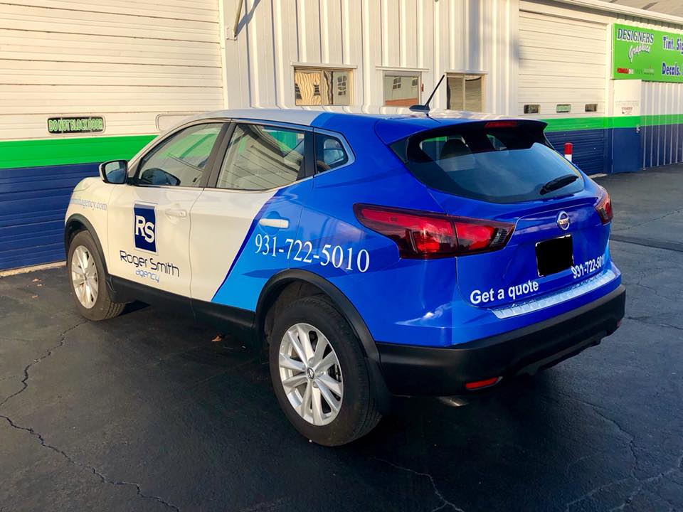 A blue and white car is parked in front of a building.