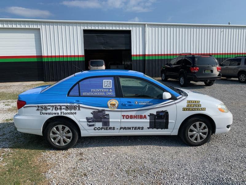 A blue and white car is parked in front of a building.