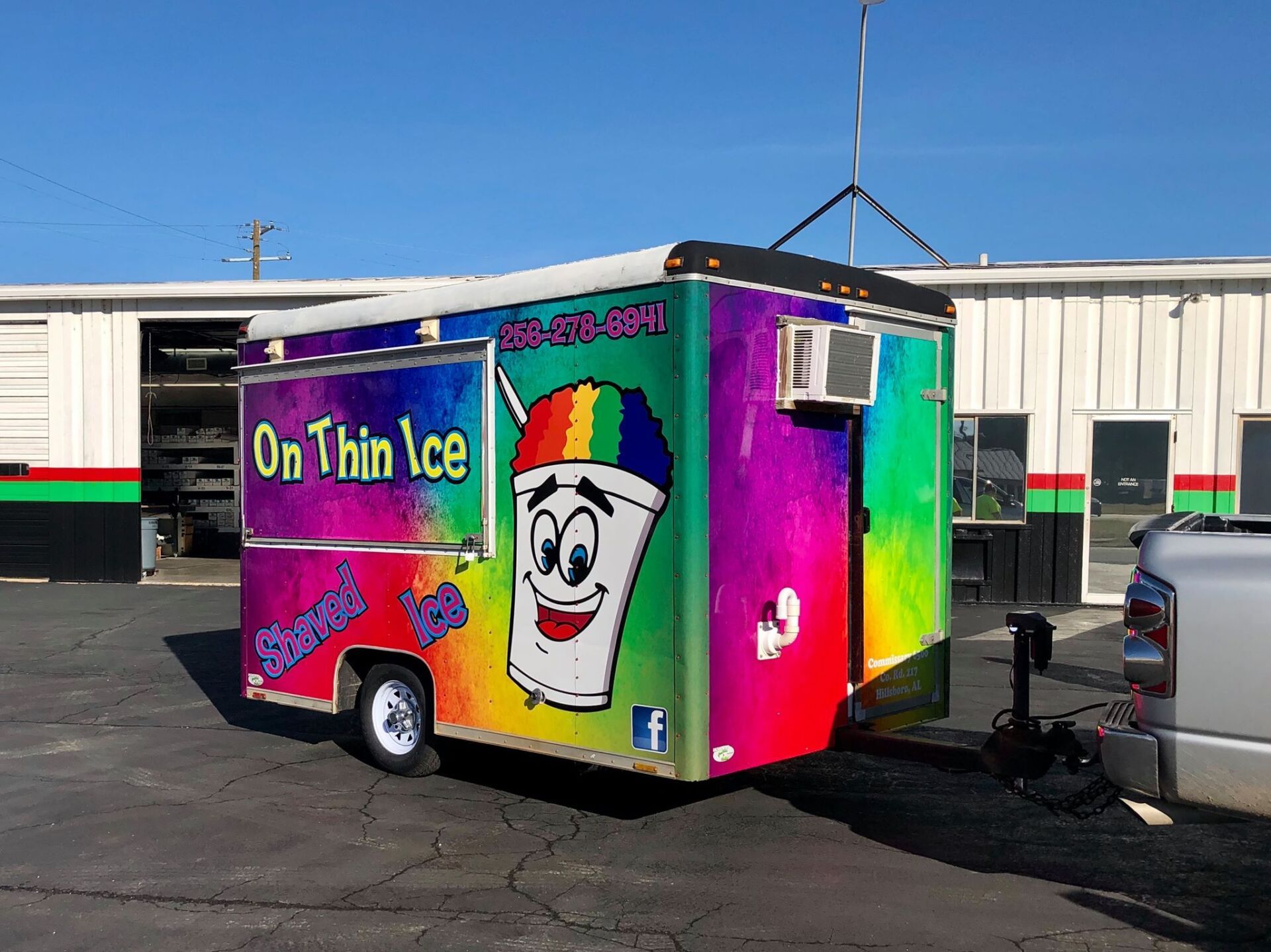 A colorful food truck is parked in front of a building.