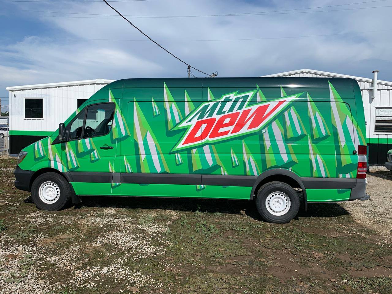 A green mtn dew van is parked in a grassy field.