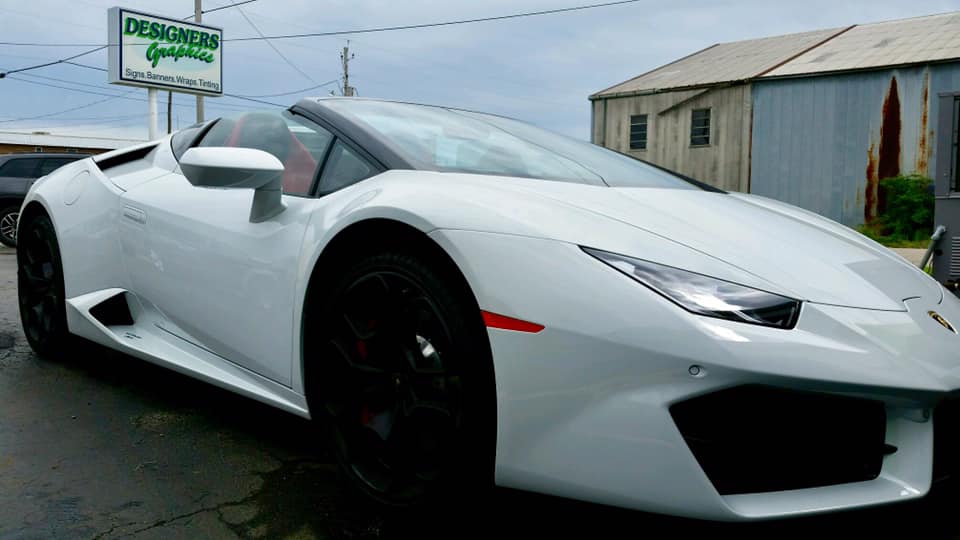 A white lamborghini is parked in front of a building