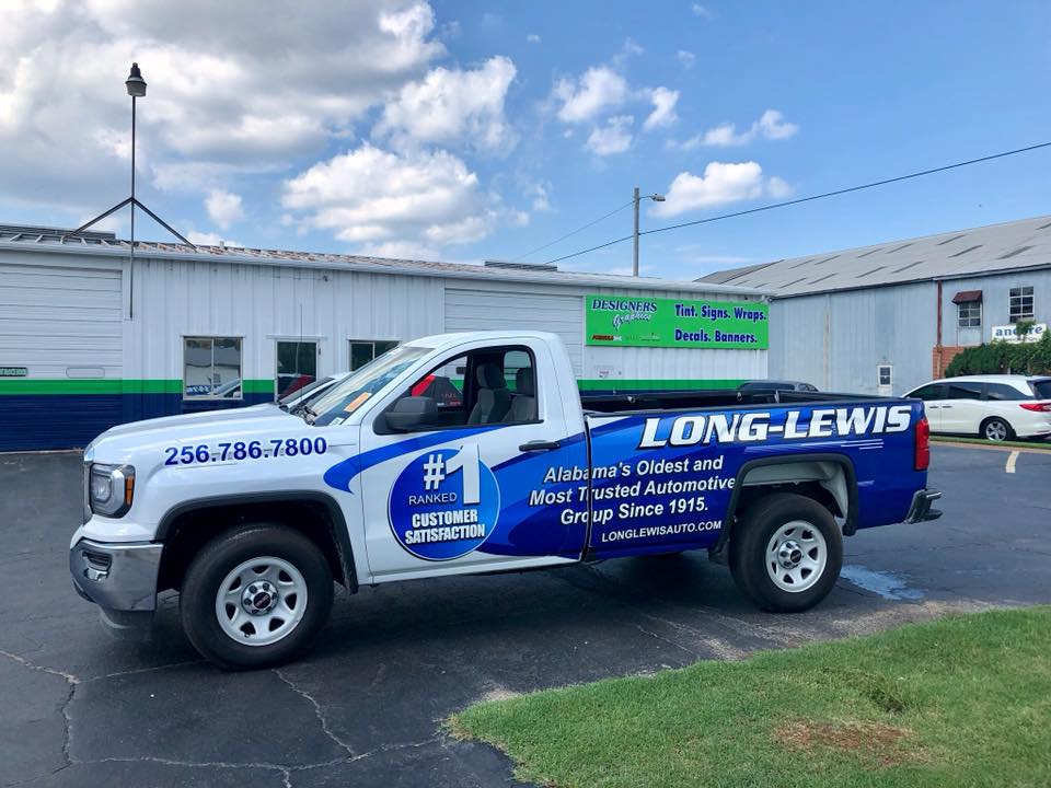 A long lewis truck is parked in front of a building.