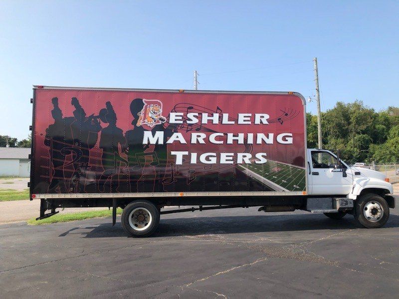 A white truck with a red sign that says reshler marching tigers
