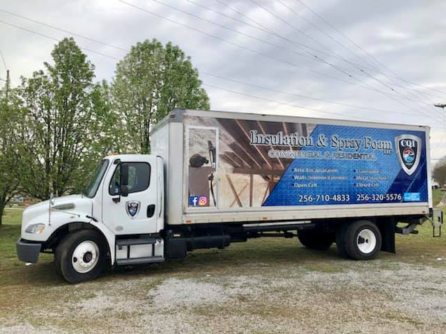 A white truck is parked in a grassy field.