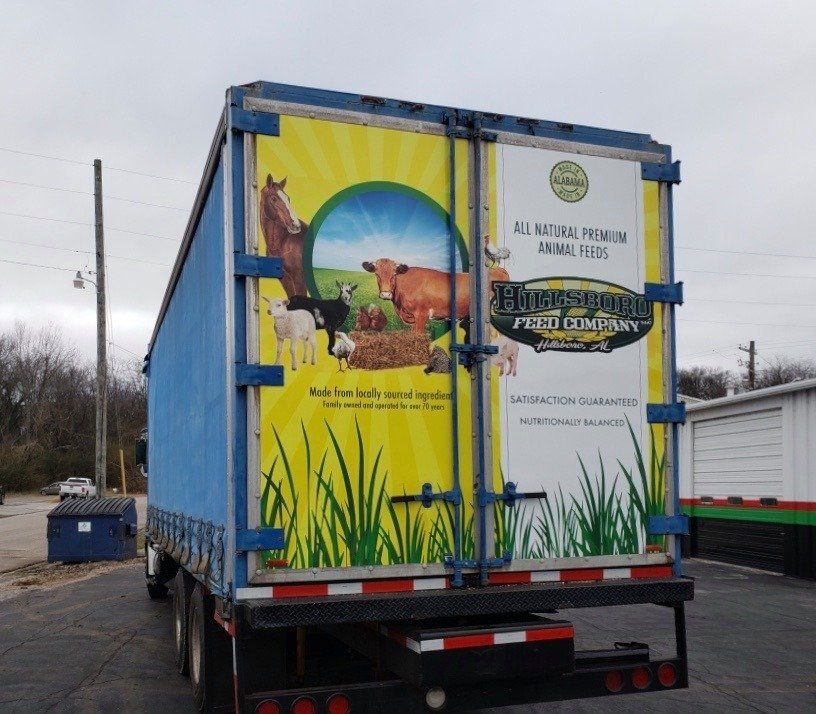 A blue trailer with a yellow and white advertisement on the back