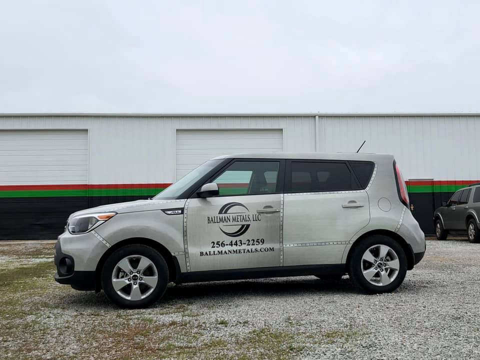 A silver car is parked in front of a building.