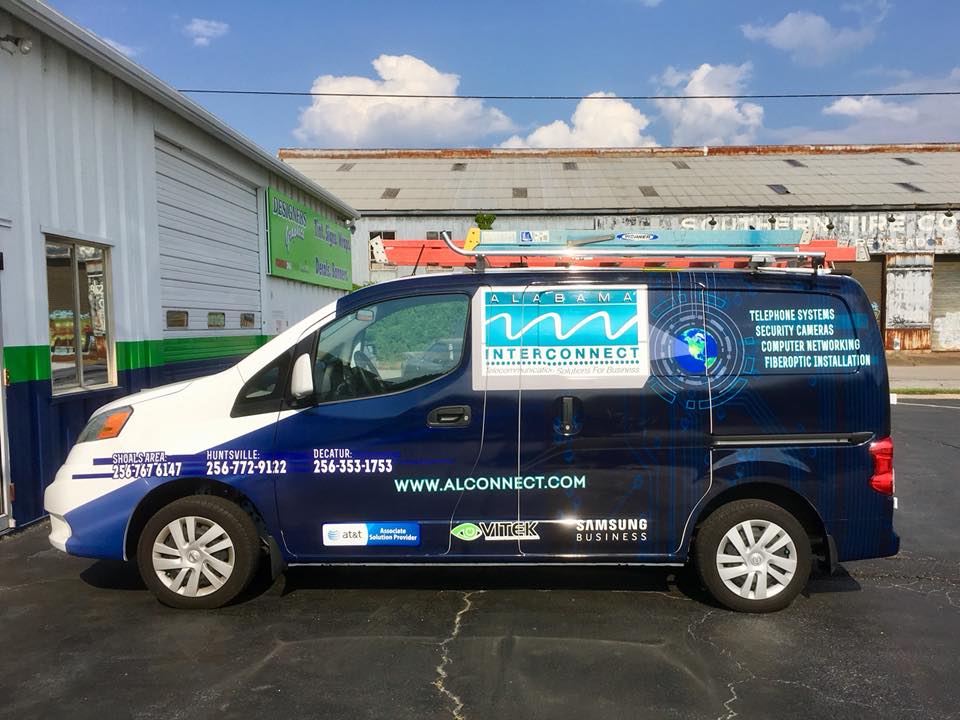 A blue and white van is parked in front of a building.