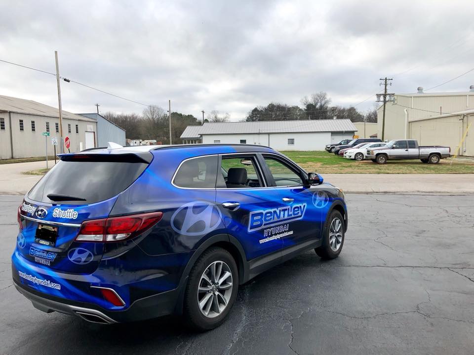 A blue hyundai santa fe is parked on the side of the road.