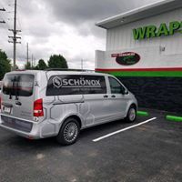 A silver van is parked in a parking lot in front of a building.