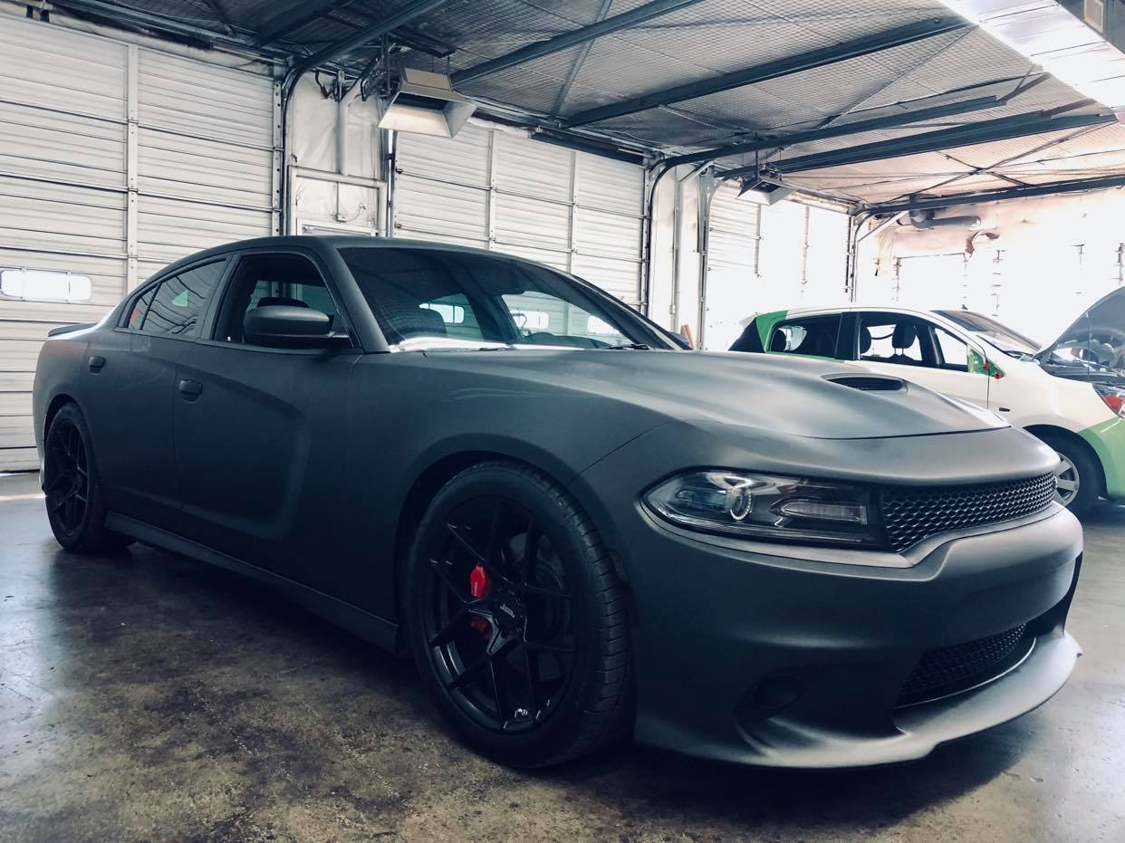A black dodge charger is parked in a garage.